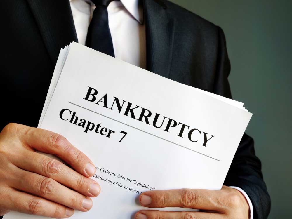 Man in suit holder papers labelled "Bankruptcy Chapter 7"