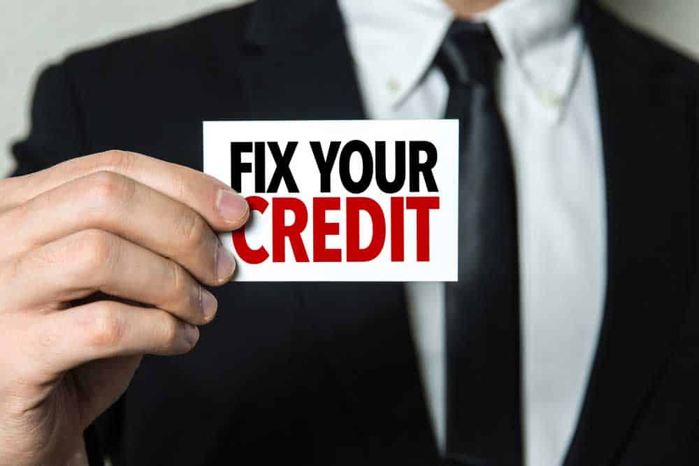 Business man holding a card with the text "Fix Your Credit"