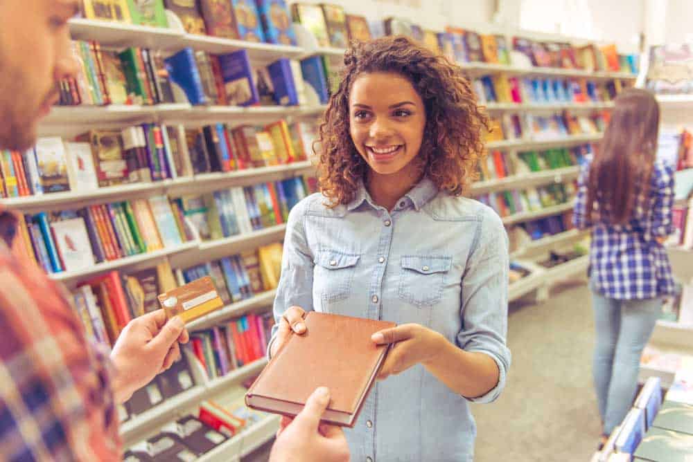 Beautiful woman in a book store buying a book using her credit card