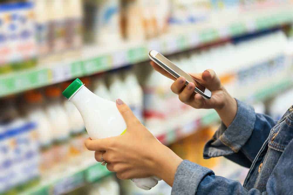 Mystery shopper taking a picture of a milk bottle with her smartphone