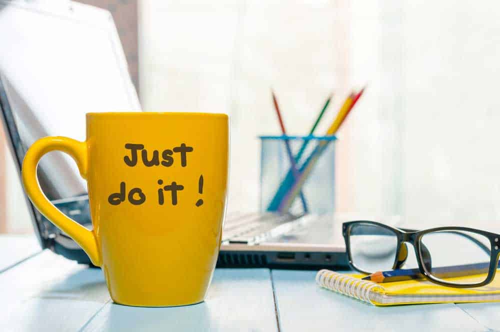 Busy office table with a coffee cup with the words "Just do it!"