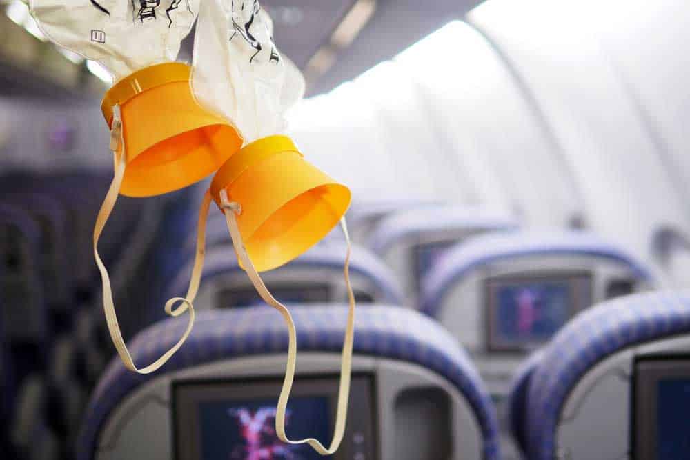 Oxygen mask dangling from the ceiling in a plane cabin.