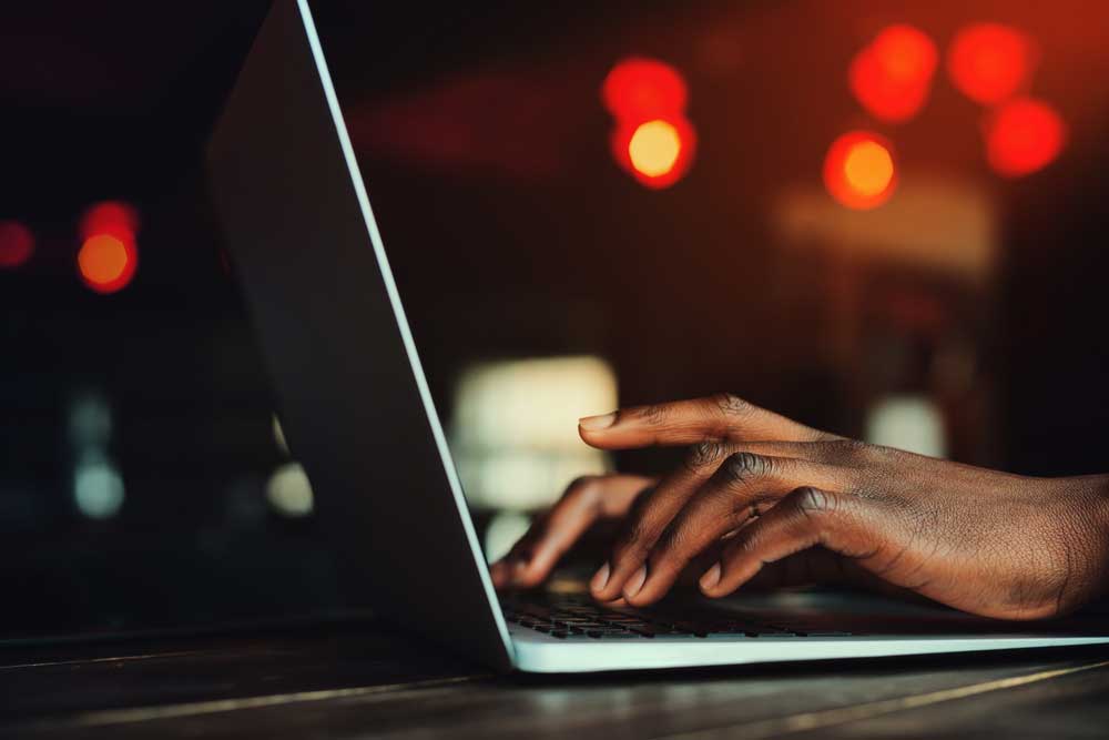 Black mans hands writing a business letter on a laptop