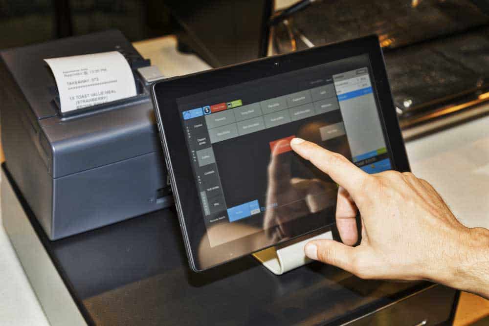 Finger pressing a screen on a point of sales (POS) terminal.