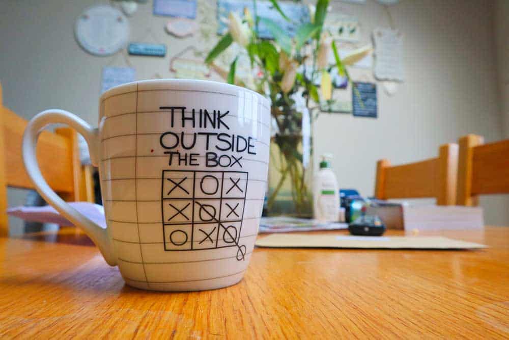 A coffee mug on a table with the words "Think outside the box".