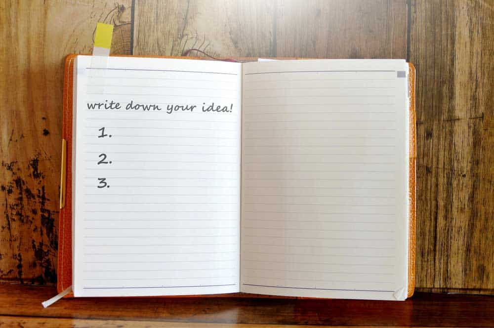 Notebook on a table with the sentence "write down your idea!".